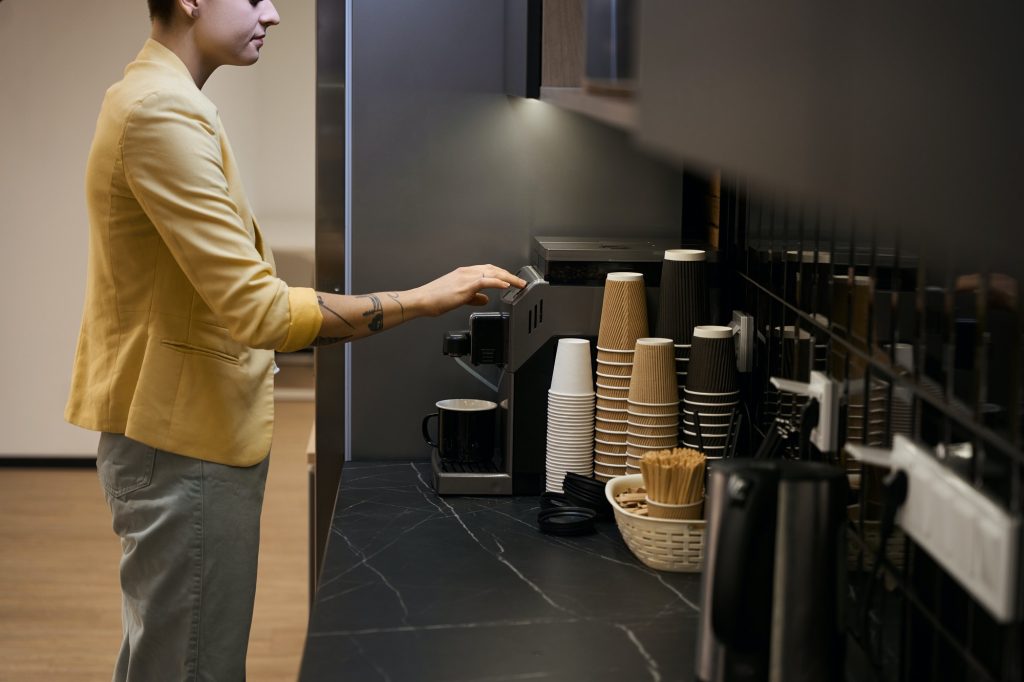 Woman making coffee in office coffee machine